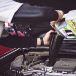 Mechanic working under a car on the exhaust system, illustrating catalytic converter theft and insurance coverage