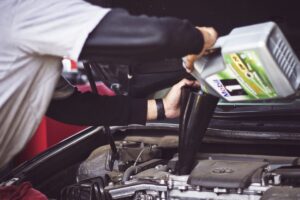 Mechanic working under a car on the exhaust system, illustrating catalytic converter theft and insurance coverage