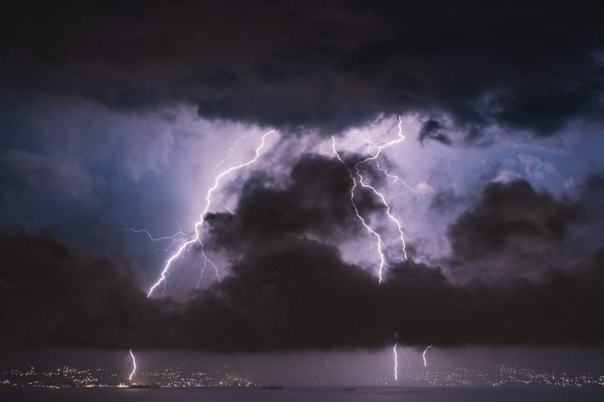 Lightning striking near a house at night, illustrating power surge damage and homeowners insurance coverage