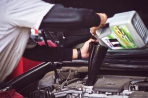 Mechanic inspecting the underside exhaust system of a car, illustrating catalytic converter theft coverage