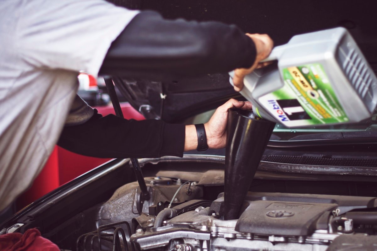 Mechanic inspecting the underside exhaust system of a car, illustrating catalytic converter theft coverage